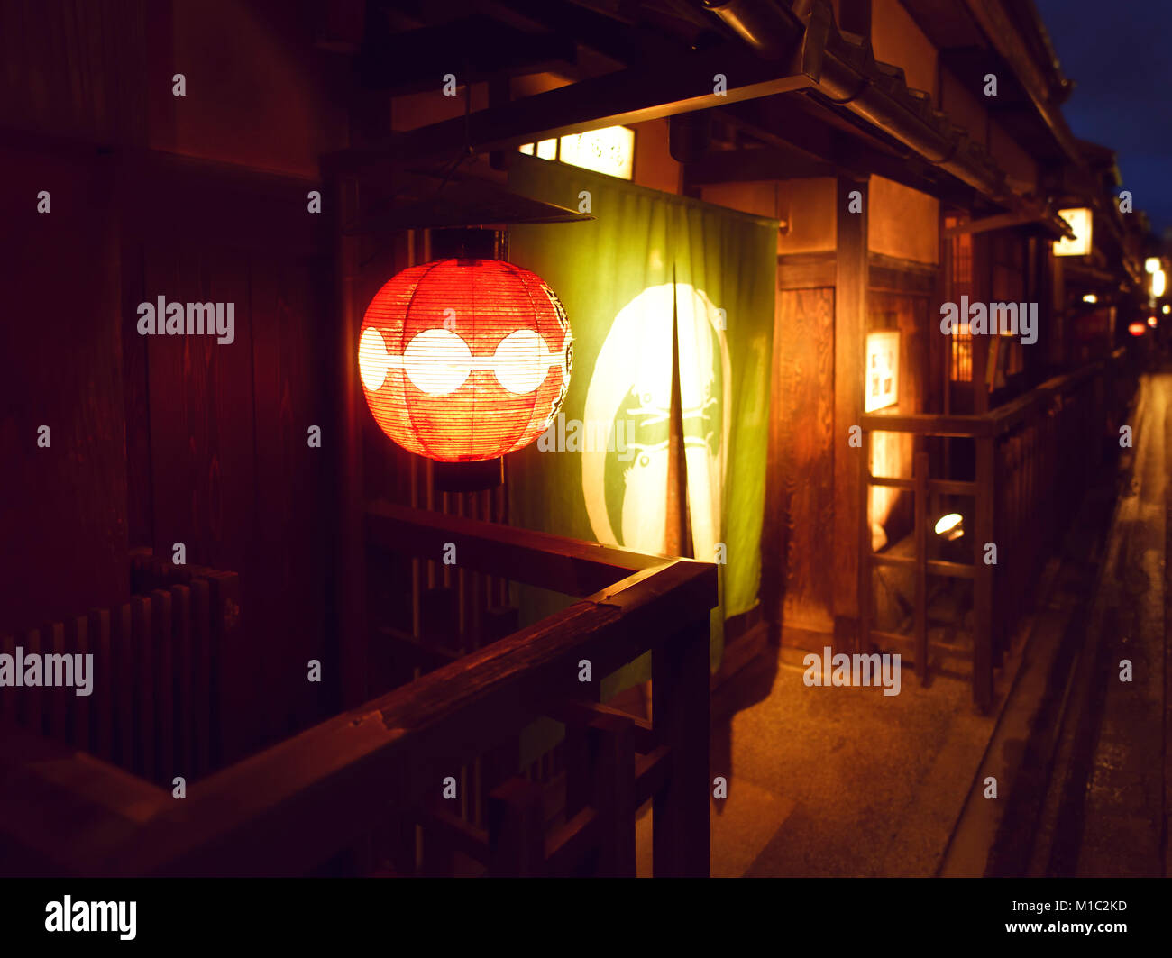 Tsudaro, traditional teahouse red lantern by the entrance door lit up at night and Noren, fabric divider with a shop sign, at Hanamikoji Dori street i Stock Photo