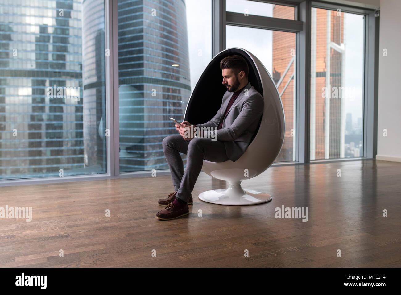 Business man sitting in a chair in a modern office Stock Photo - Alamy