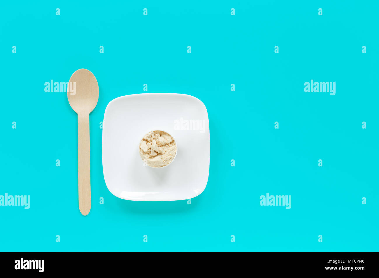Protein Powder In Scoop On Small Plate With Wooden Spoon Stock