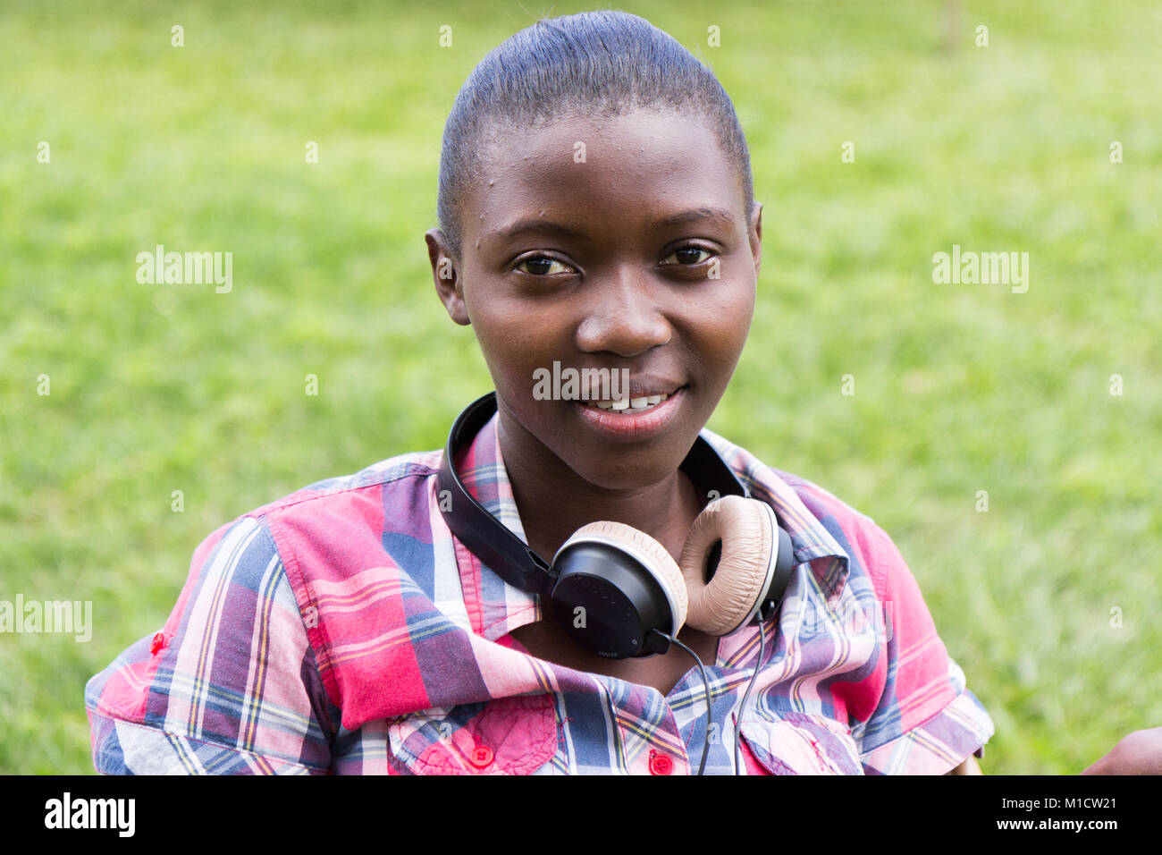 A beautiful smiling young Ugandan woman with headphones around her neck Stock Photo