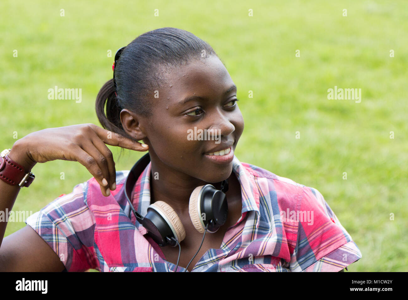 A beautiful smiling young Ugandan woman with headphones around her neck Stock Photo