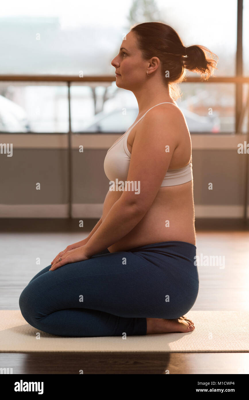 Pregnant woman performing yoga at home Stock Photo
