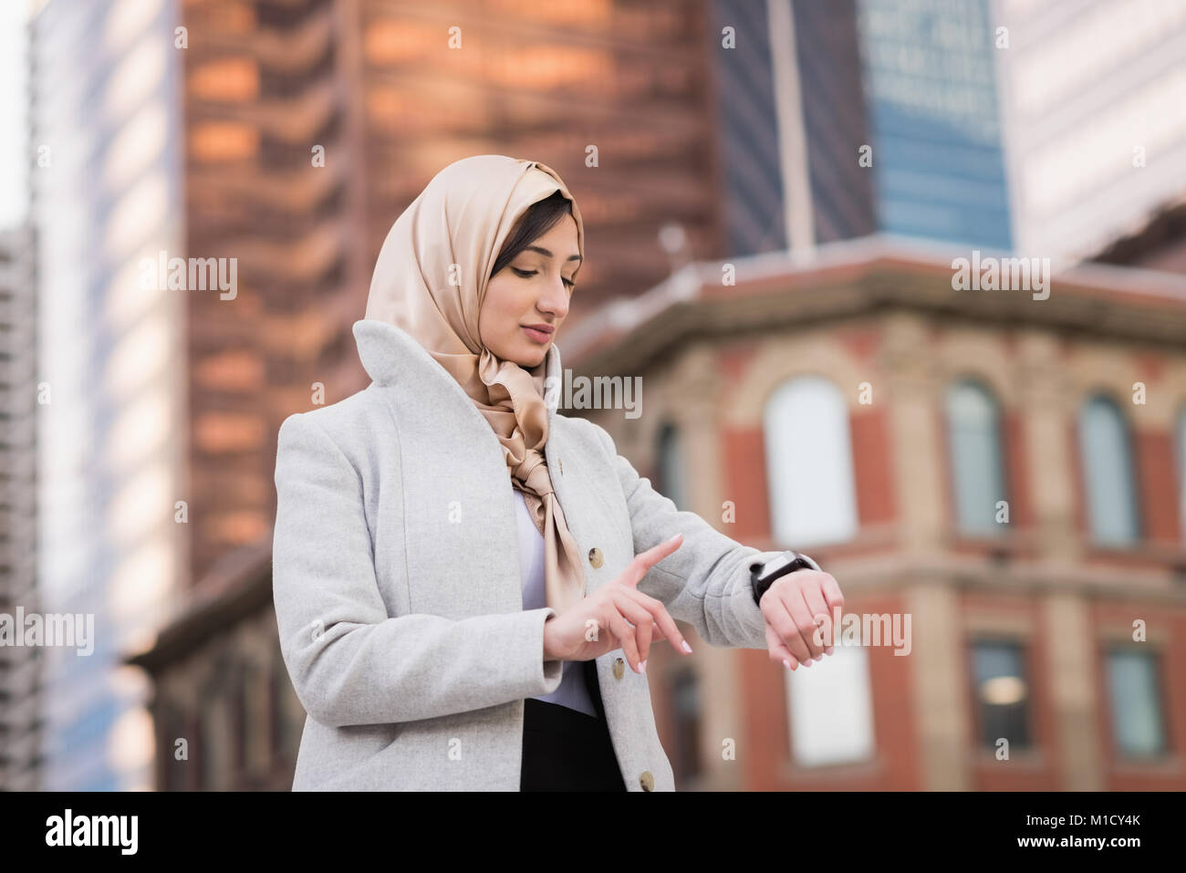 Woman in hijab using smartwatch Stock Photo