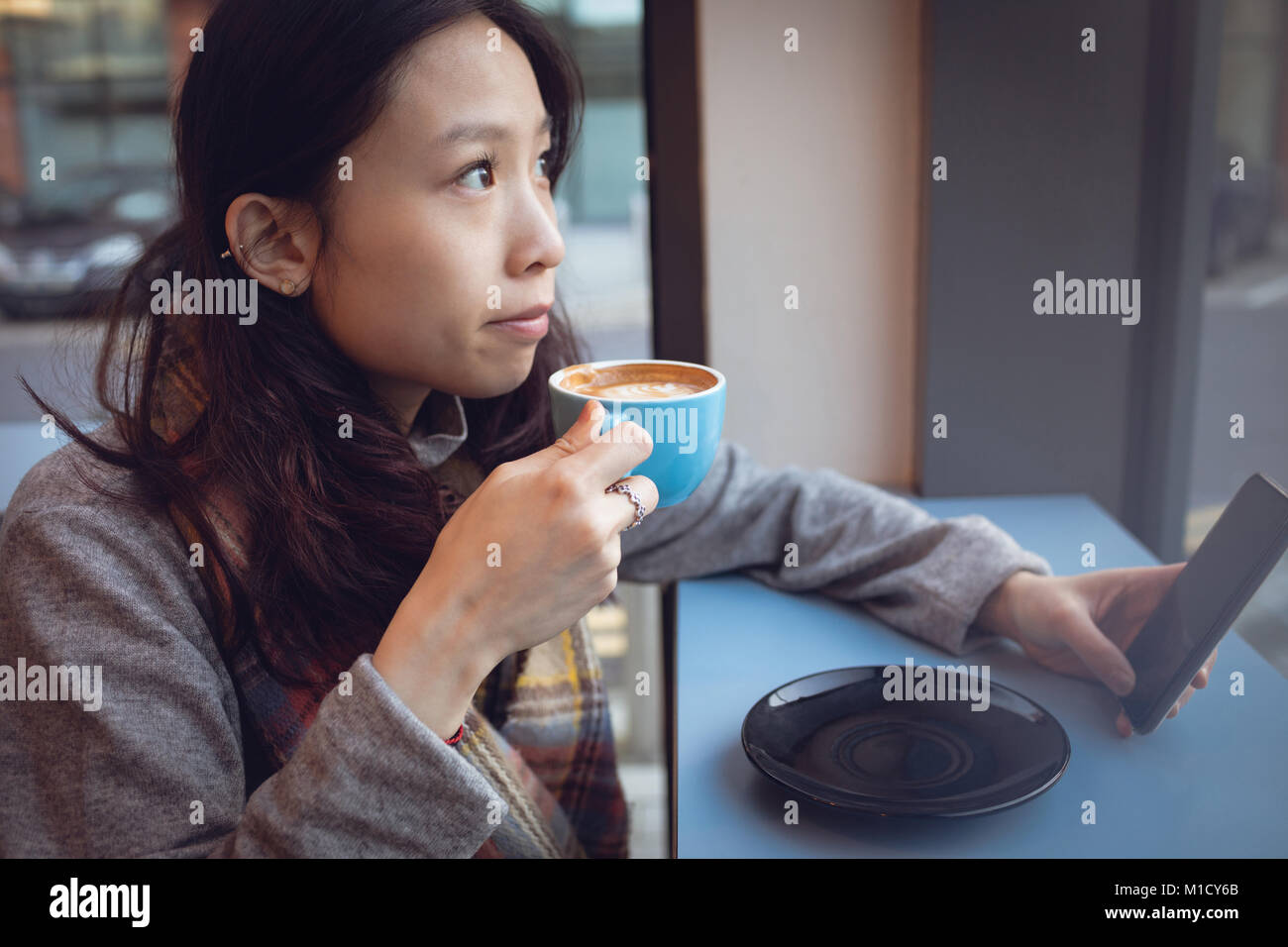 Thoughtful woman having coffee at table Stock Photo