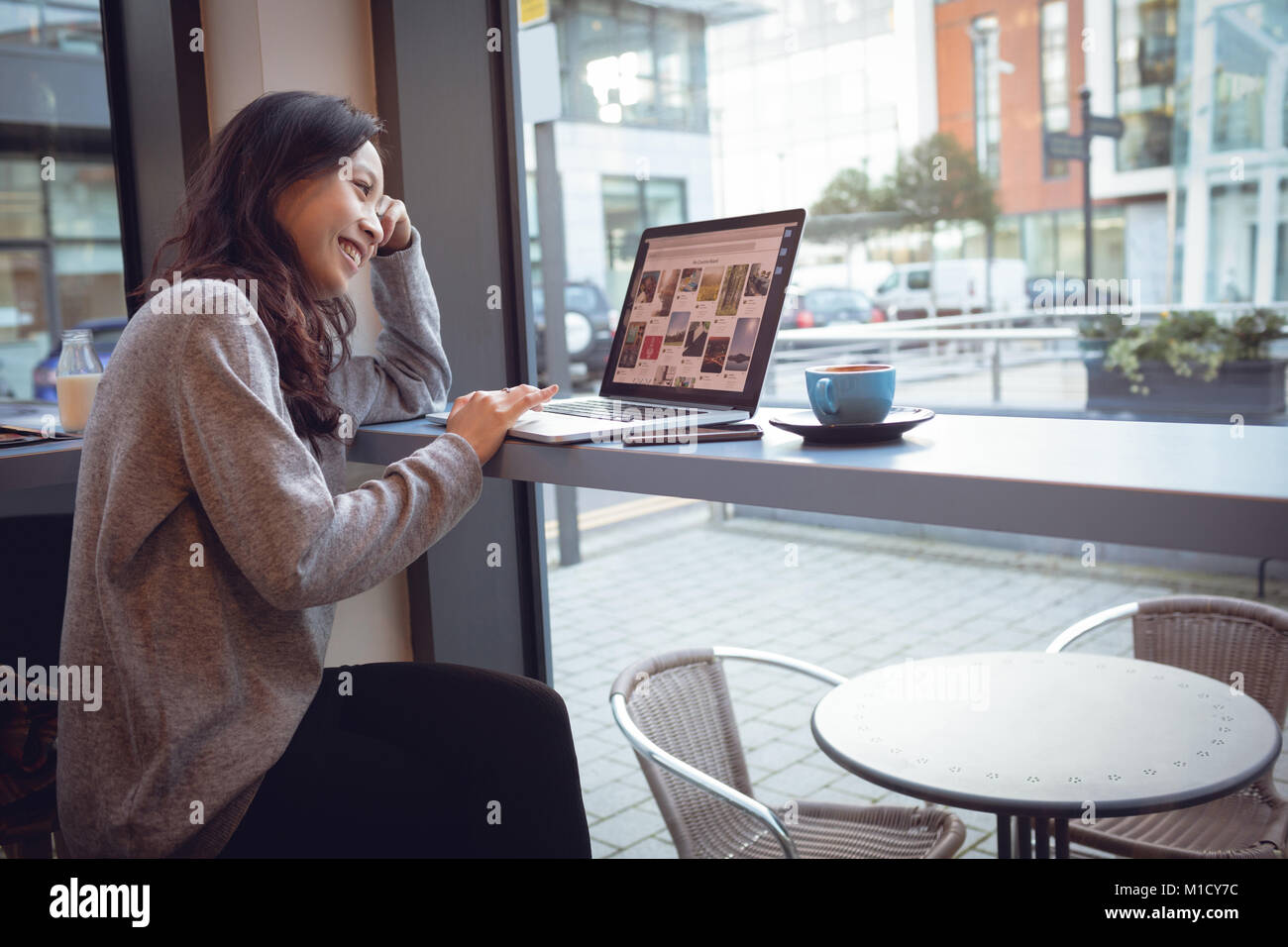 Beautiful woman using laptop while having coffee Stock Photo