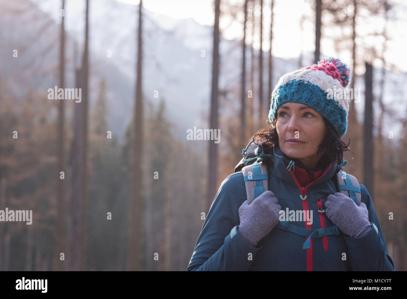 Female hiker standing with backpack in forest Stock Photo