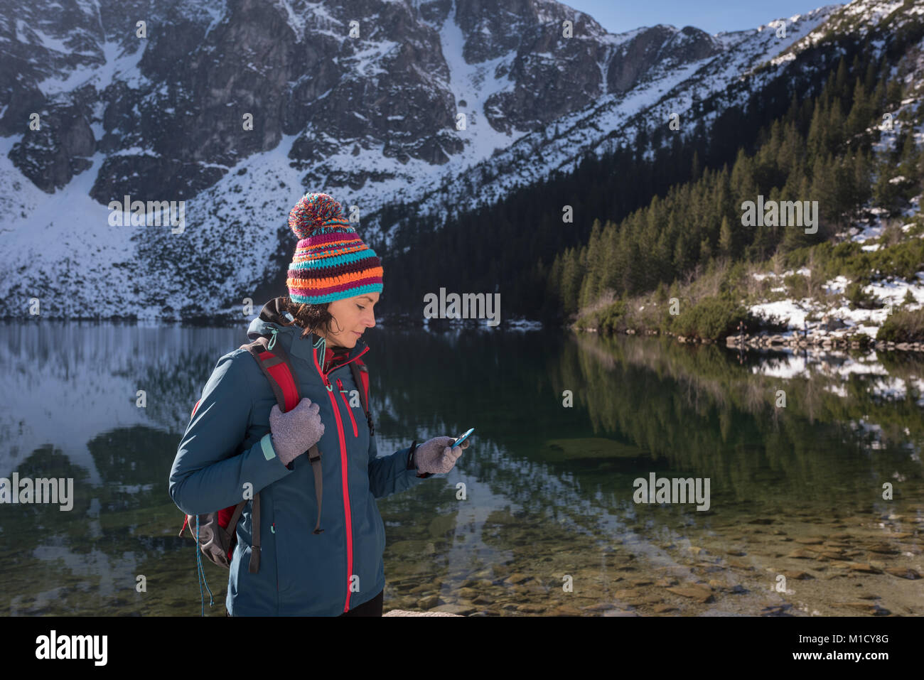Female hiker using mobile phone at lakeside Stock Photo