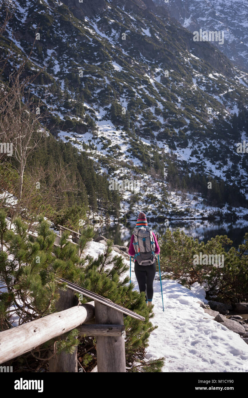 Female hiker walking at lakeside during winter Stock Photo