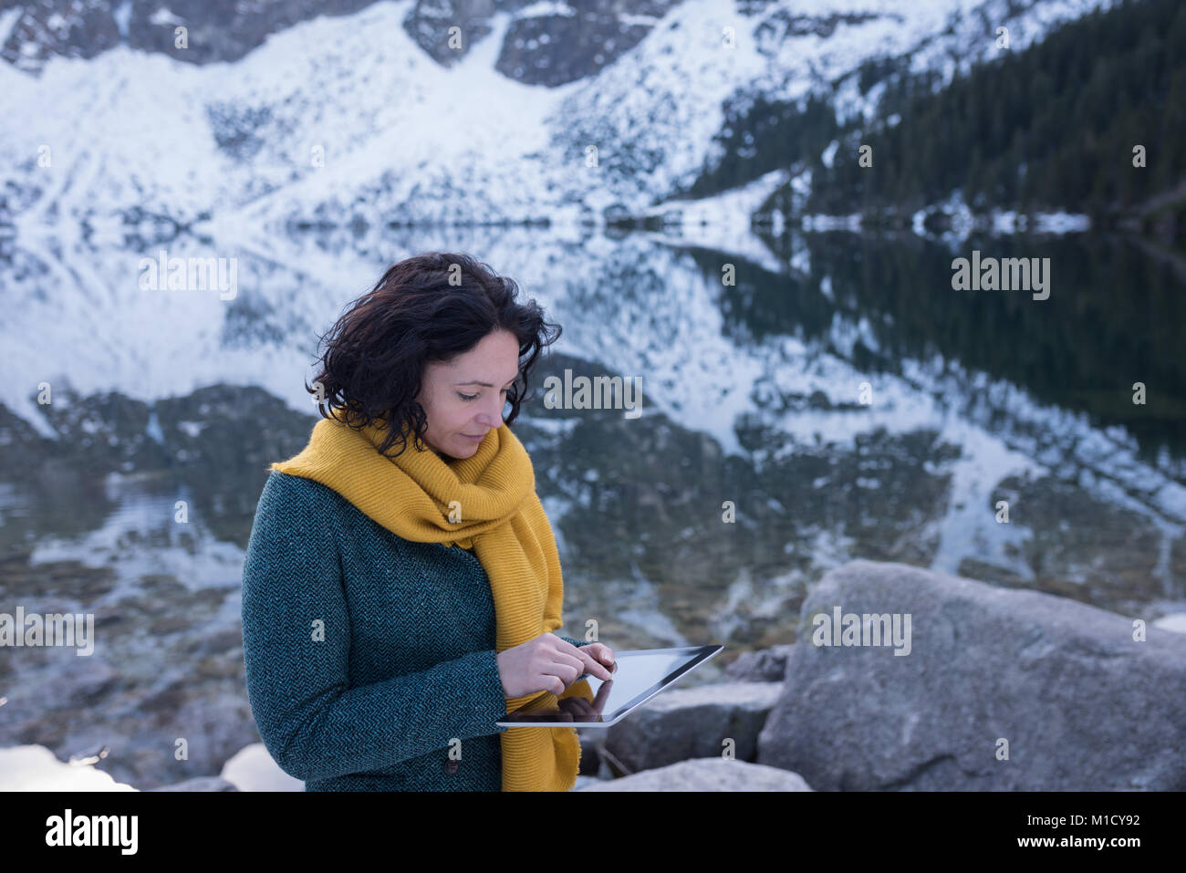 Female hiker using digital tablet at lakeside Stock Photo