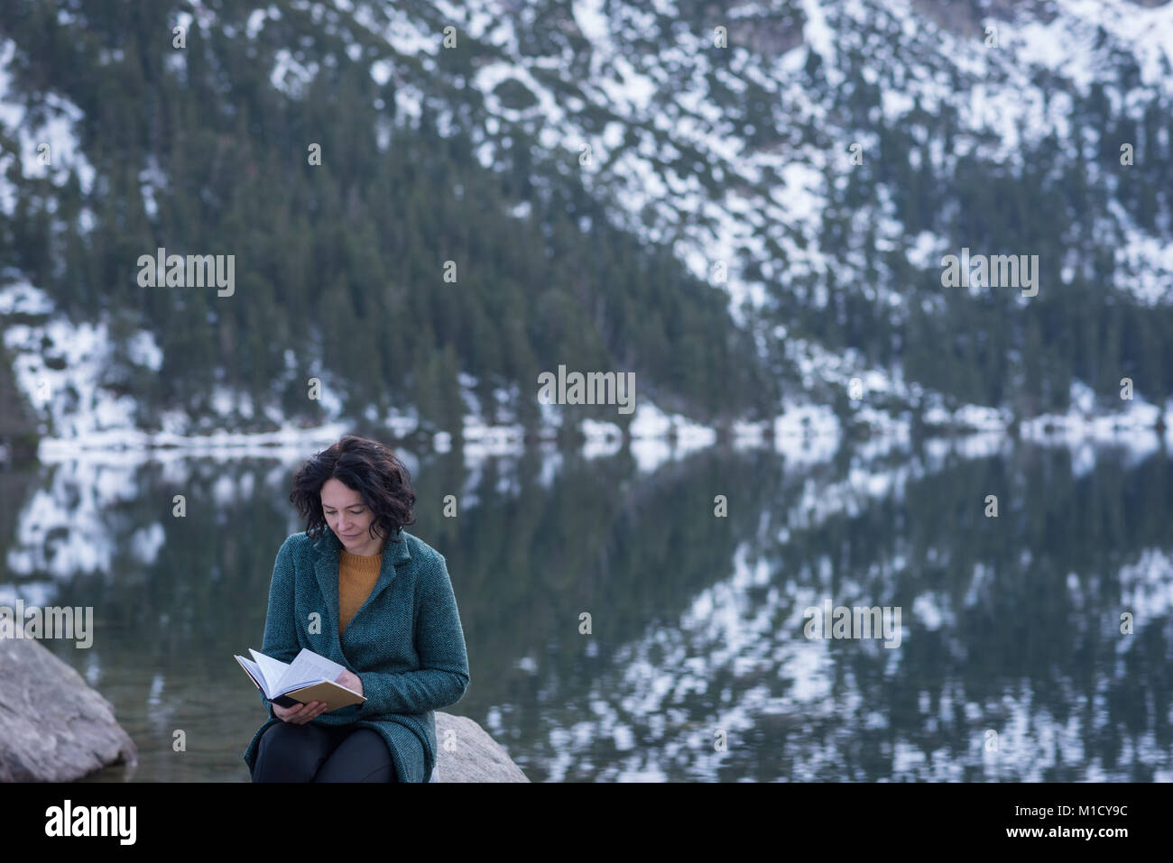 Woman reading book at lakeside Stock Photo