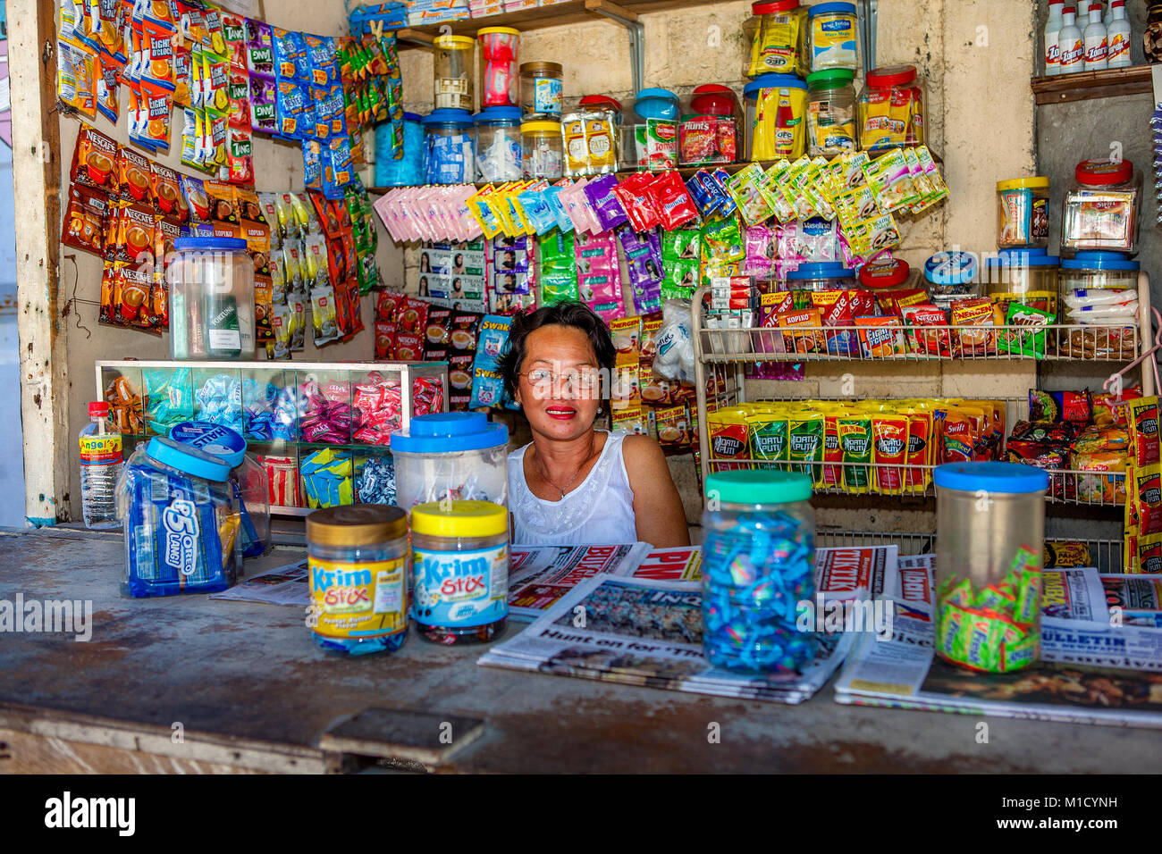 A Filipino woman tends her local sari-sari store, neighborhood convenience store, in Barretto, Luzon, Philippines. Stock Photo