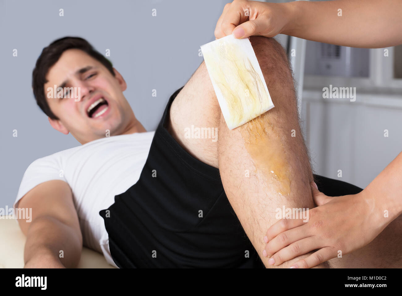 Man Screaming In Pain While Waxing Leg With Wax Strip Stock Photo Alamy