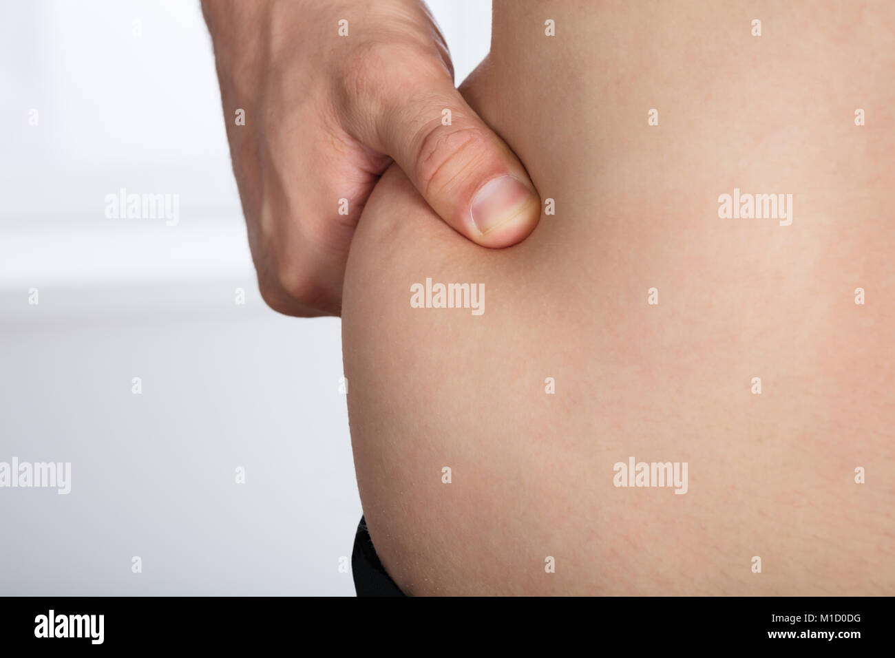 Close-up Of A Woman's Hand Pinching Excessive Stomach Fat Stock Photo