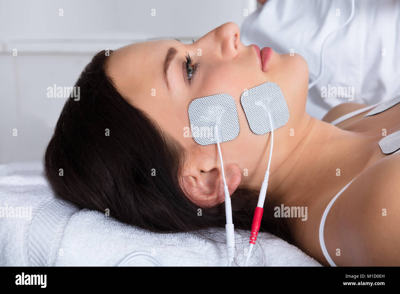Close-up Of A Young Woman Lying With Electrodes On Her Face Stock Photo