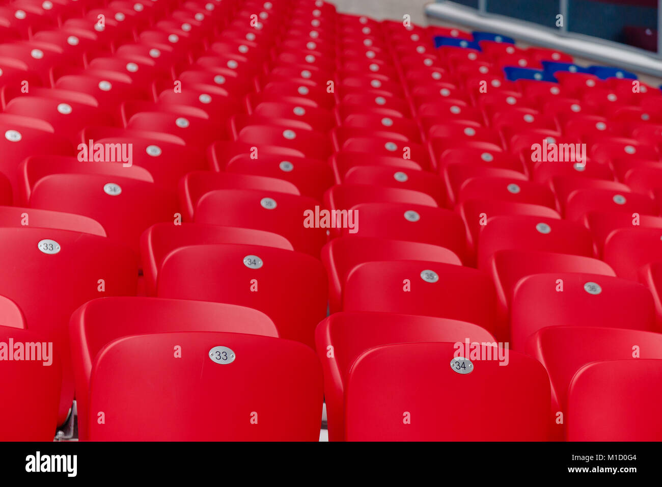 Empty red plastic chairs in a row at the football stadium. Stock Photo