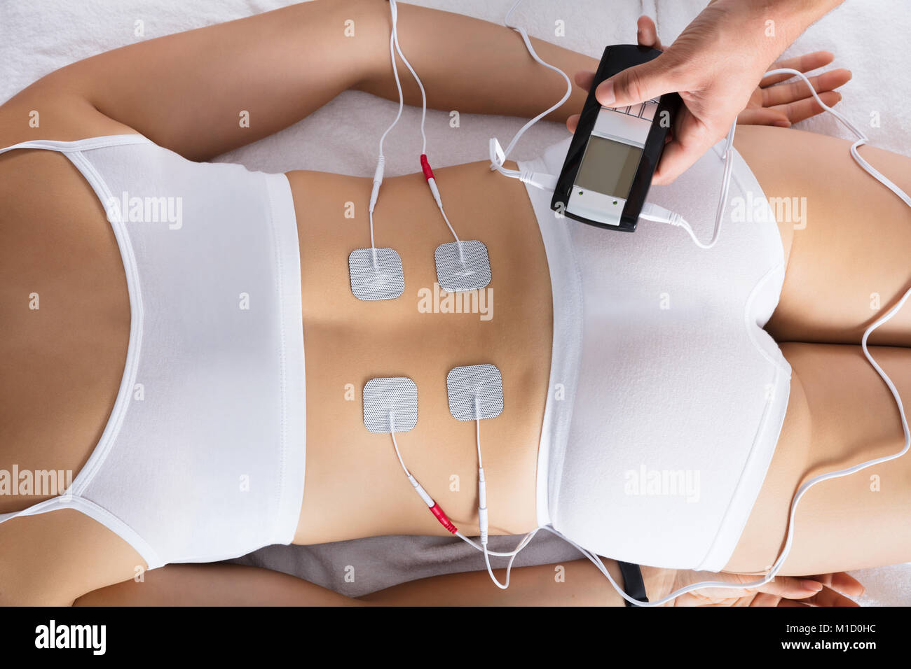 High Angle View Of A Woman Lying With Electrodes On Her Back Stock Photo