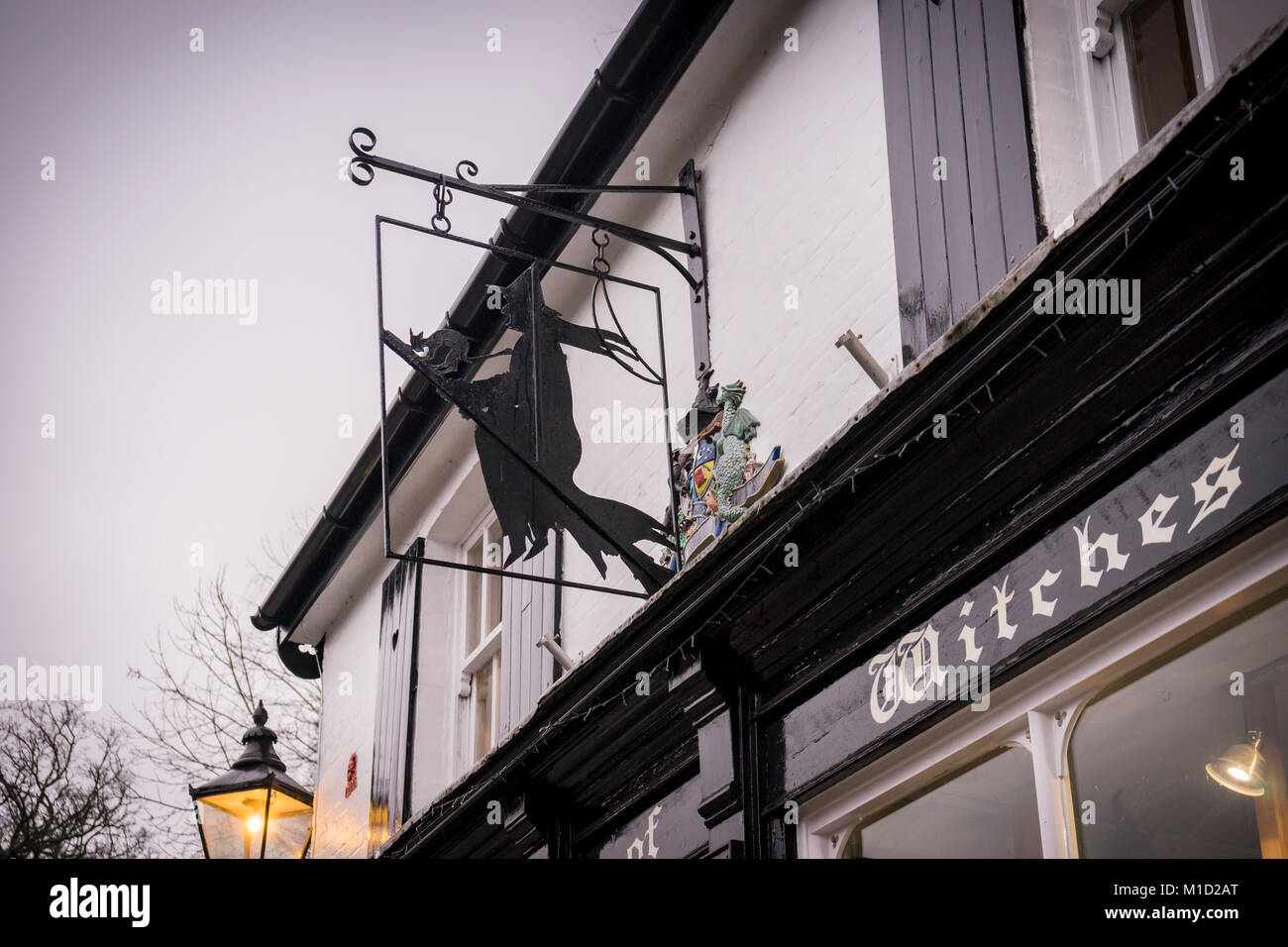 'Coven of Witches' new age shop with quirky shop sign in the shape of a flying witch in Burley on a rainy day in the New Forest, Hampshire, England,UK Stock Photo
