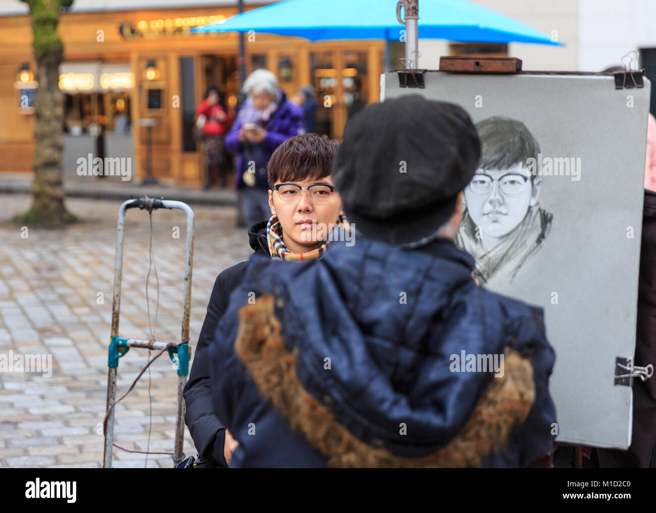 A painter sketches a young man on Place du Tertre, the famous artists square and tourist attraction in Montmartre, Paris Stock Photo