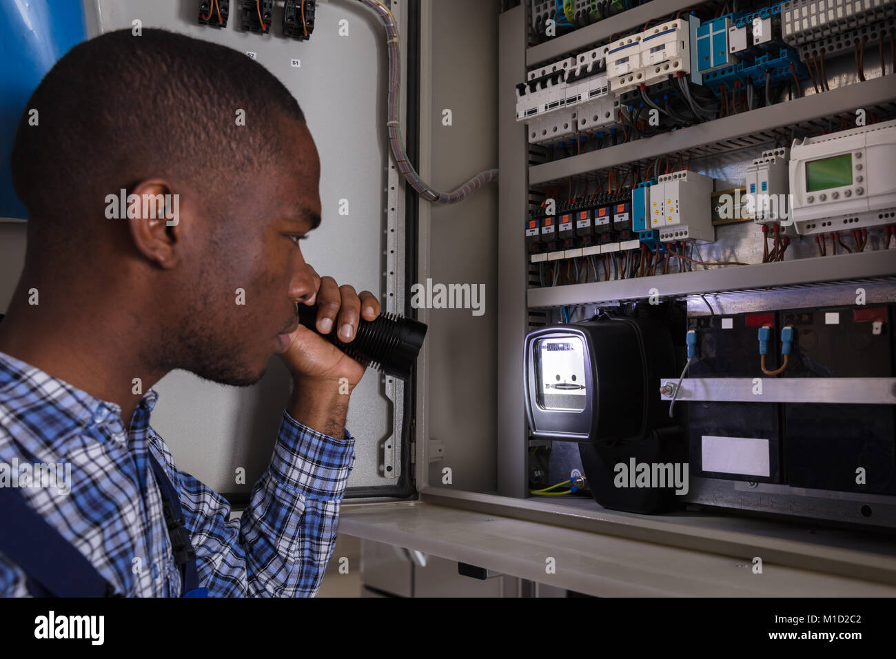 Close-up Of A Electrician Examining A Electric Meter With A Torch Stock Photo