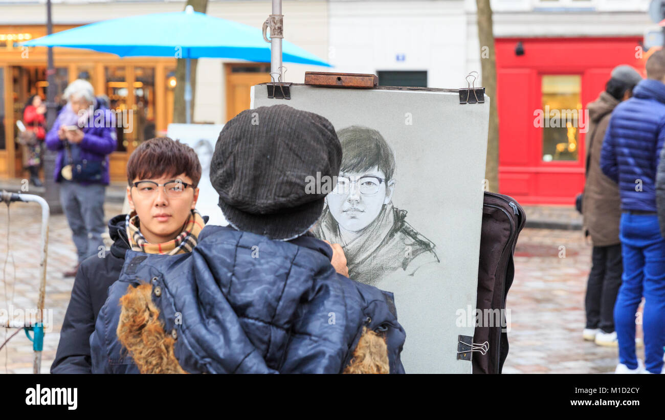 A painter sketches a young man on Place du Tertre, the famous artists square and tourist attraction in Montmartre, Paris Stock Photo