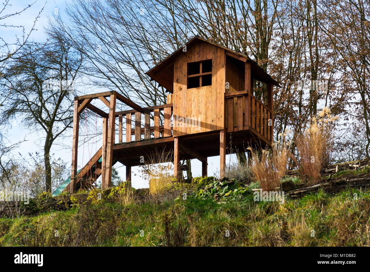 DIY wooden children playhouse with swing and slide on hillside Stock