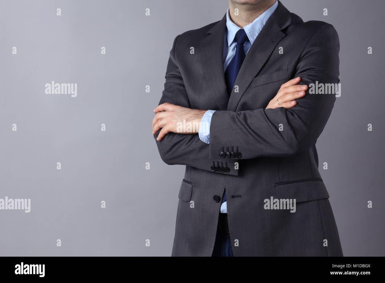 Young businessman standing with arms crossed on gray background Stock ...