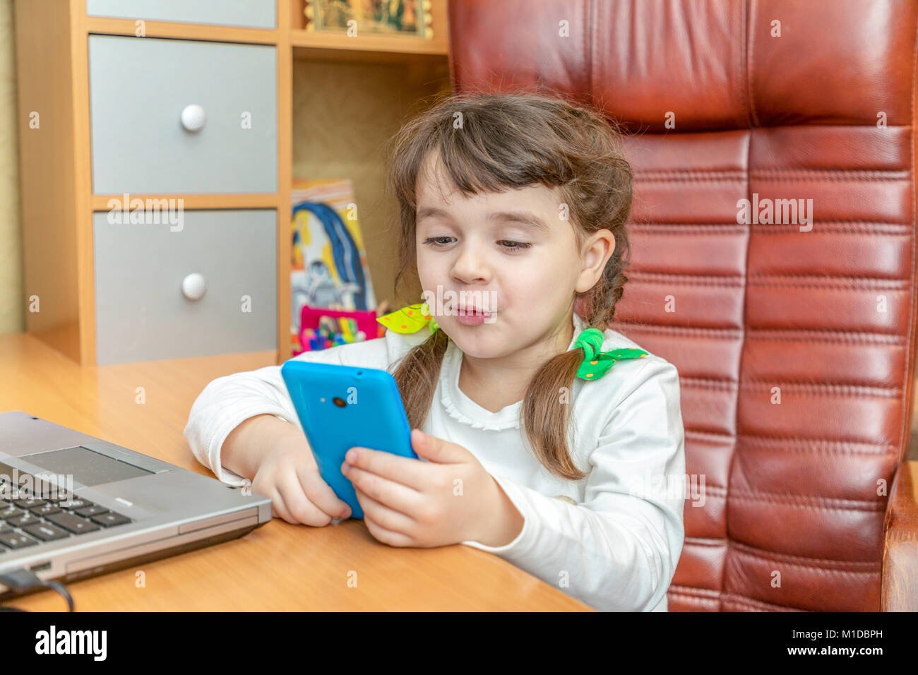 Little girl with smartphone an notebook Stock Photo