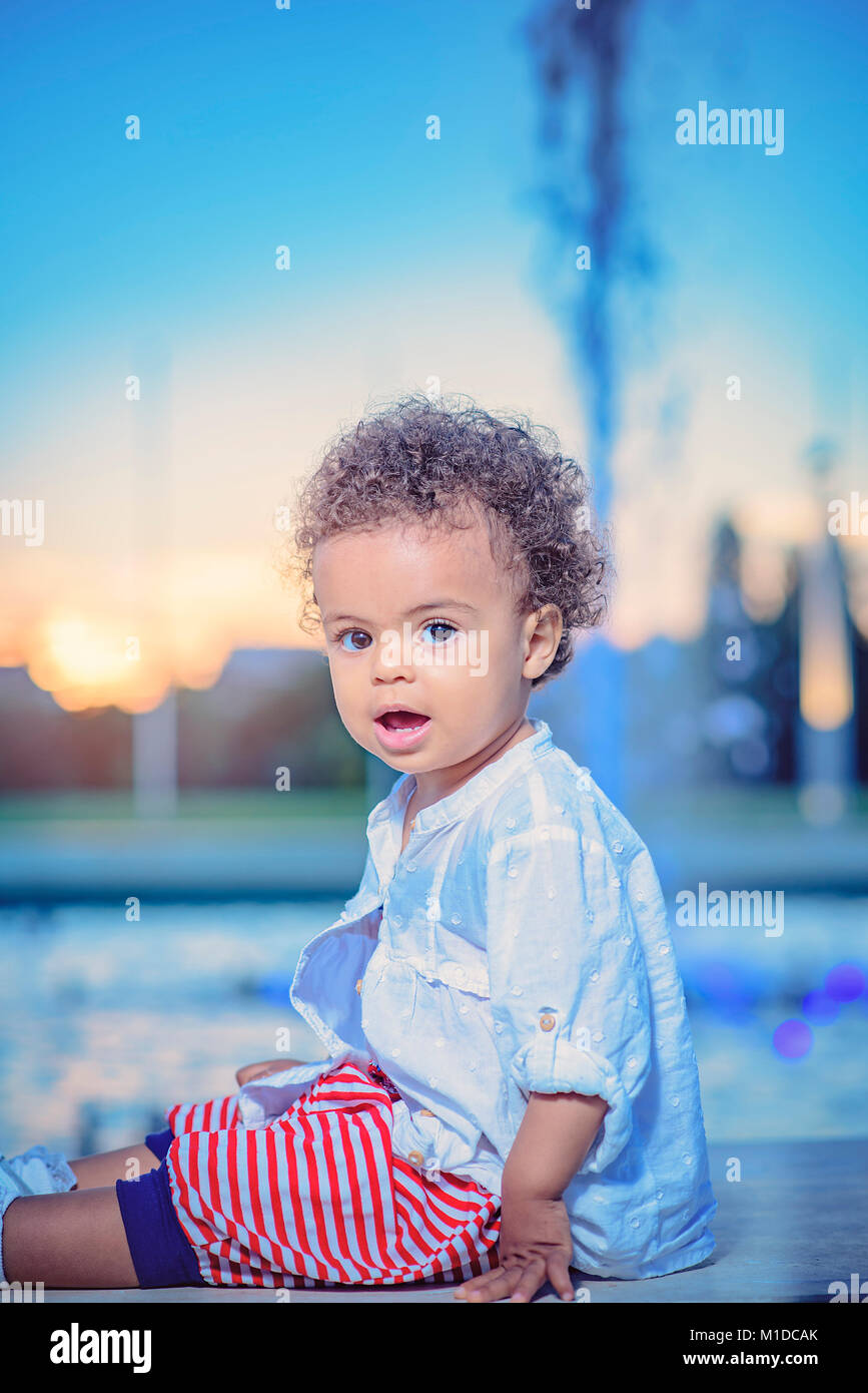 Cute baby girl playing next to fountain sprinklers Stock Photo
