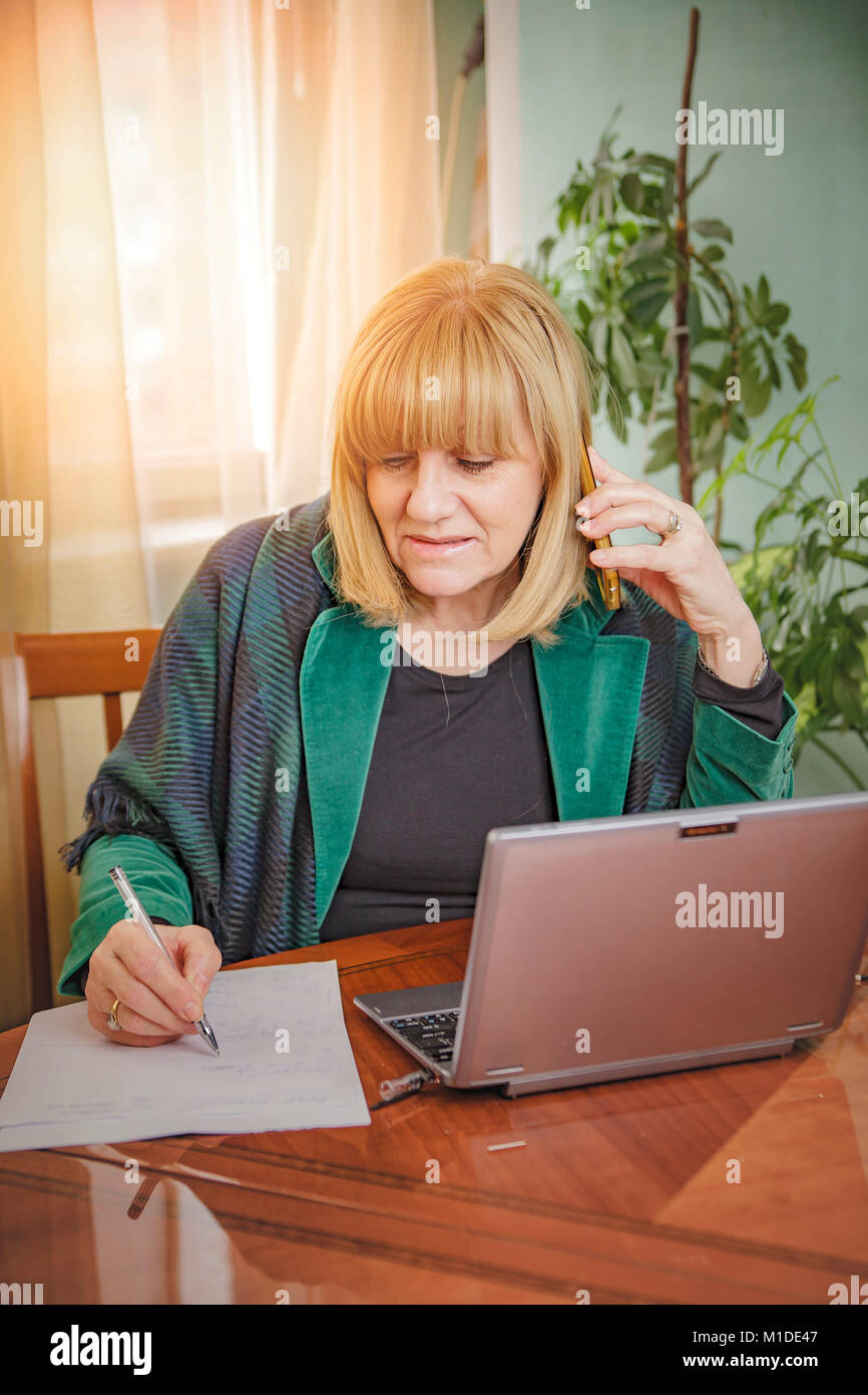 Elderly lady writing down orders, work from home Stock Photo