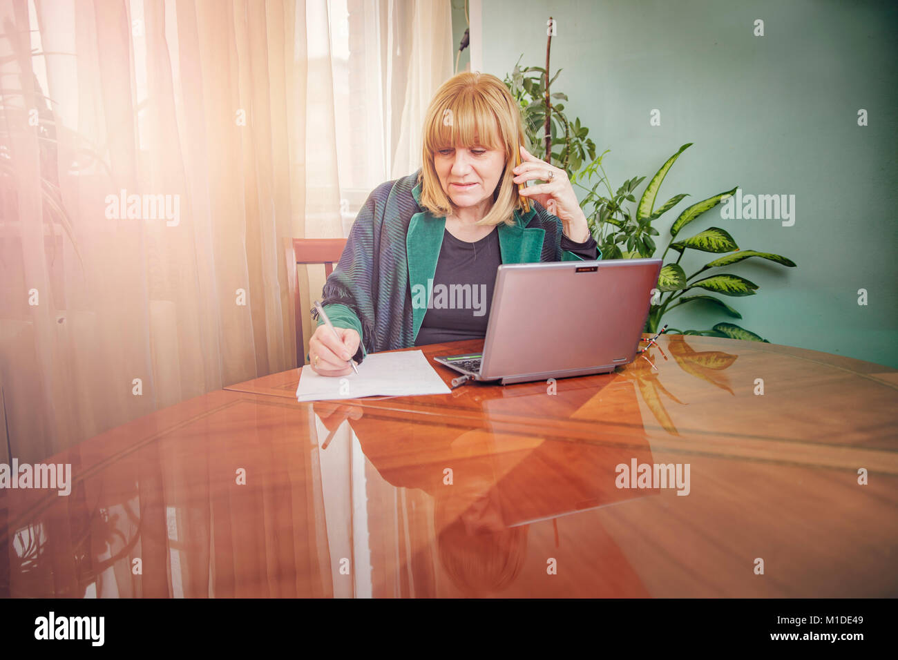Elderly lady writing down orders, work from home Stock Photo