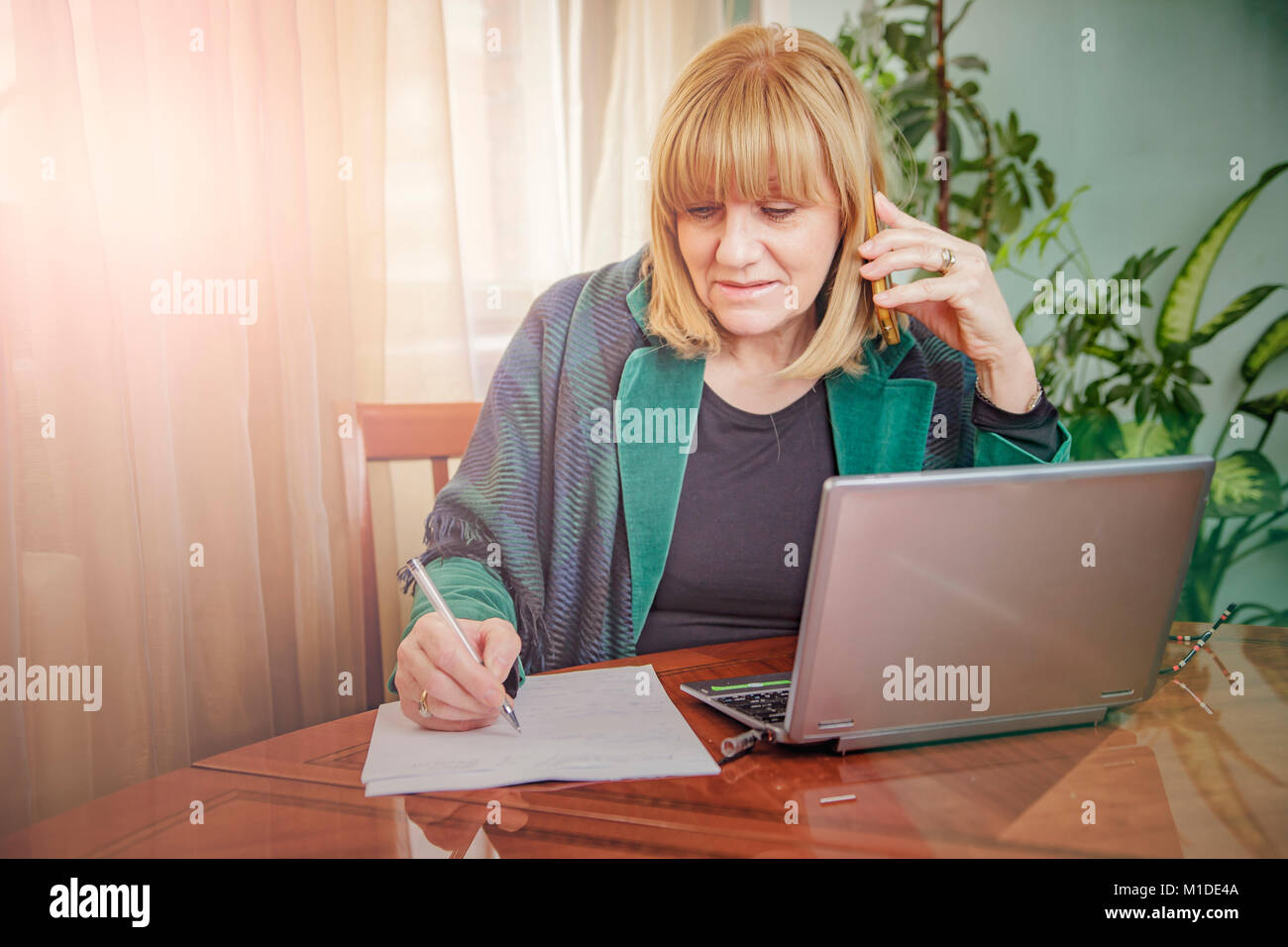 Elderly lady writing down orders, work from home Stock Photo