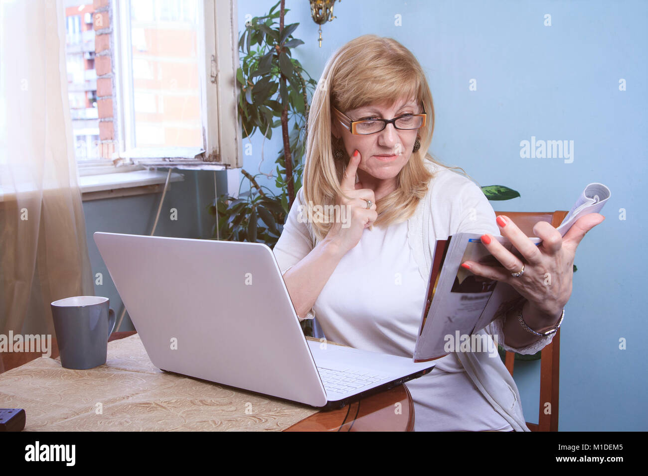 Reading a magazine and browsing computer Stock Photo