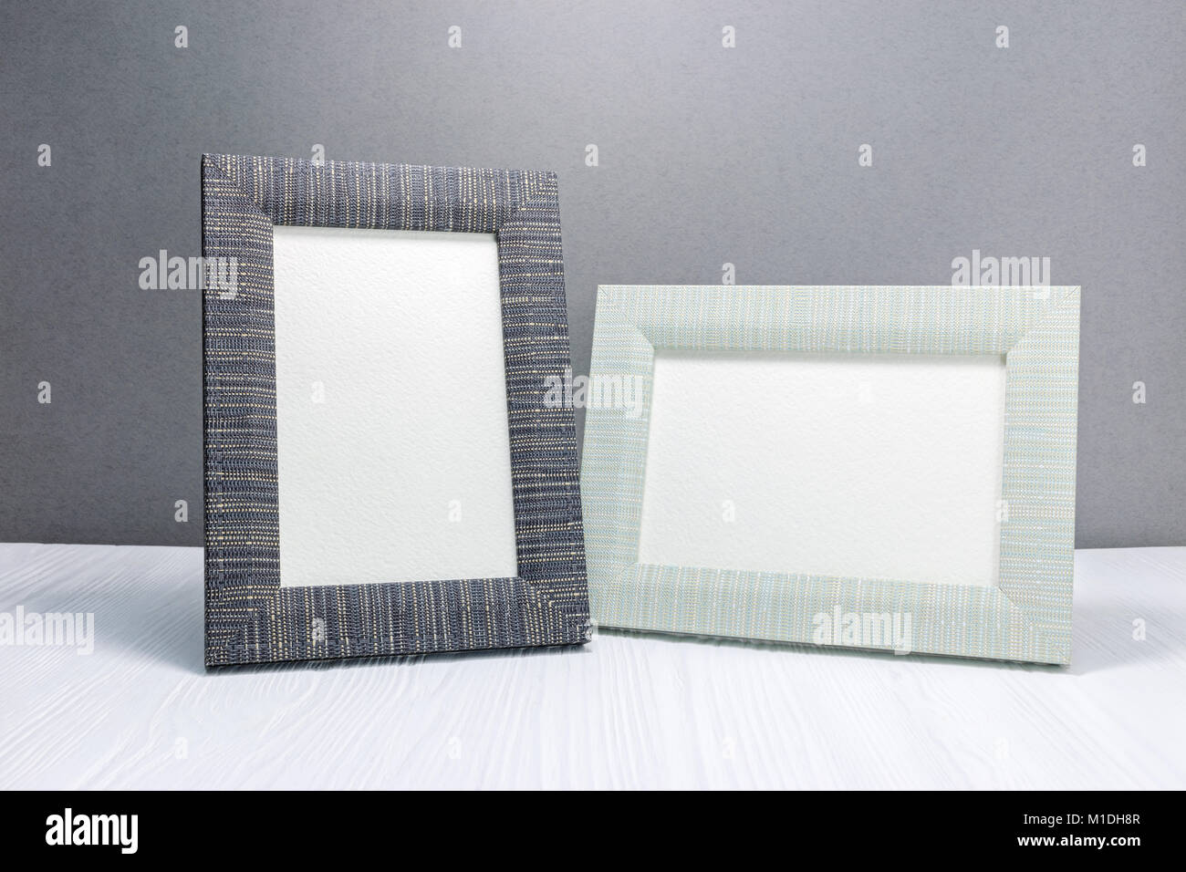 empty photo frames on white wooden table against grey wall background Stock Photo