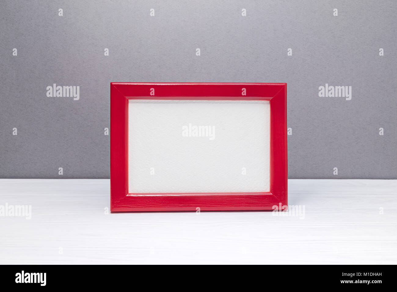 empty wooden red photo frame on grey wall background. minimalism design. Stock Photo