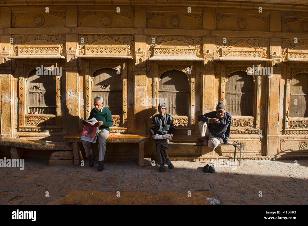 Men drinking tea in front of Patwon Ji Ki Haveli, Jaisalmer, Rajasthan, India Stock Photo