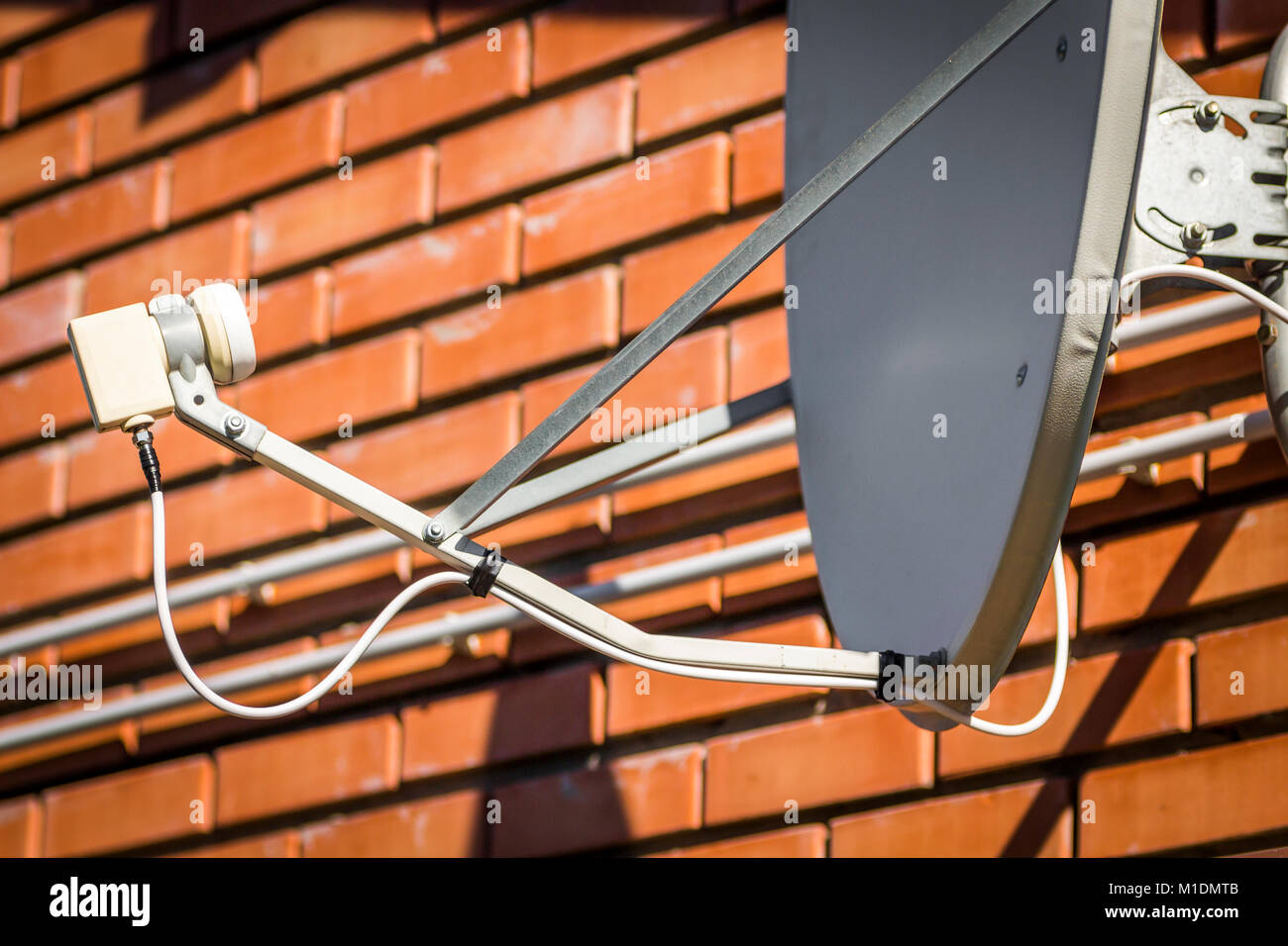 Part of a satellite dish closeup against a brick wall background Stock