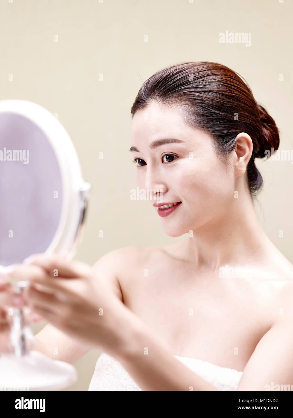 beautiful young asian woman looking at self in mirror, happy and smiling. Stock Photo