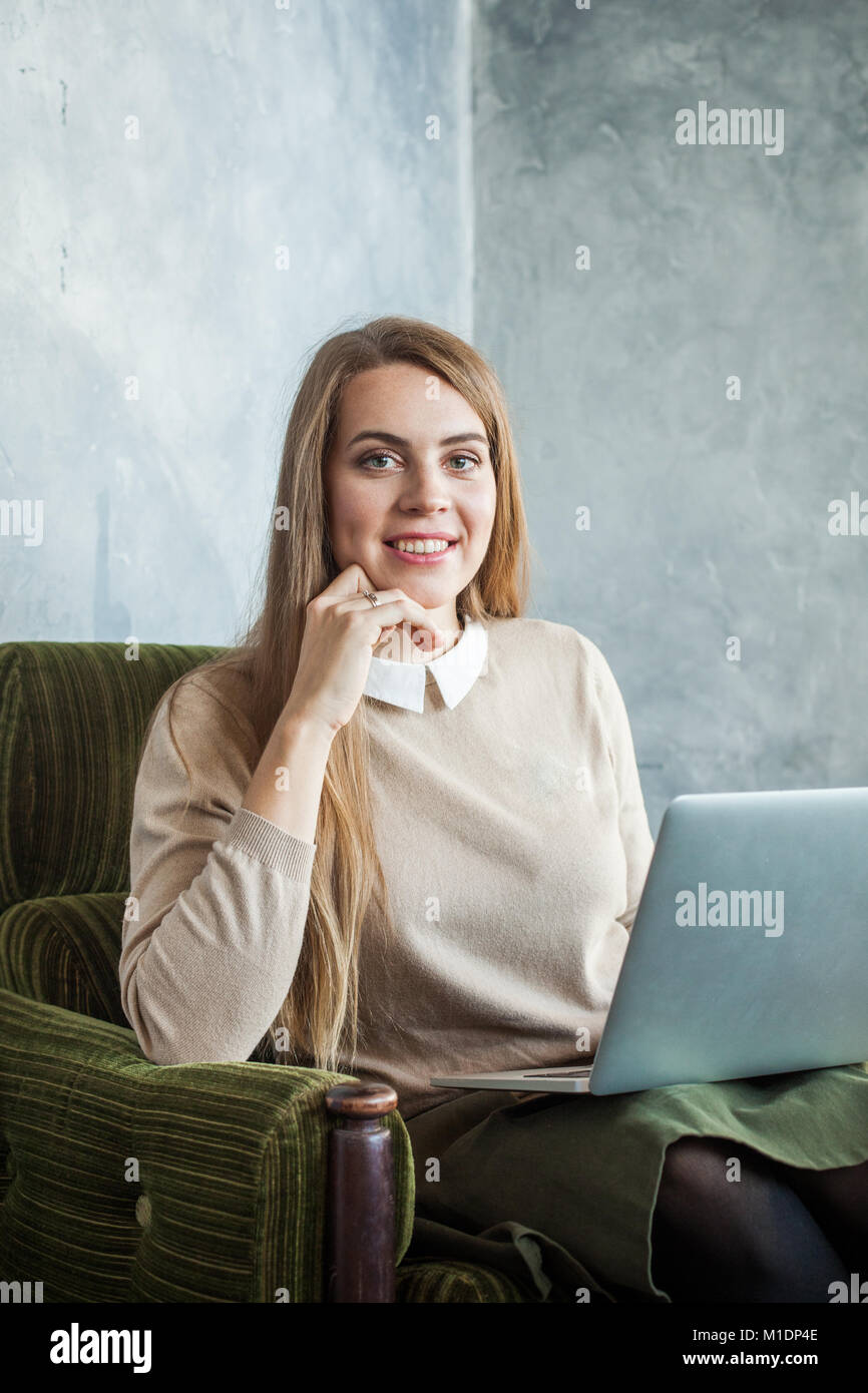 Cusual Smiling Woman Using Laptop surfing the Web Stock Photo