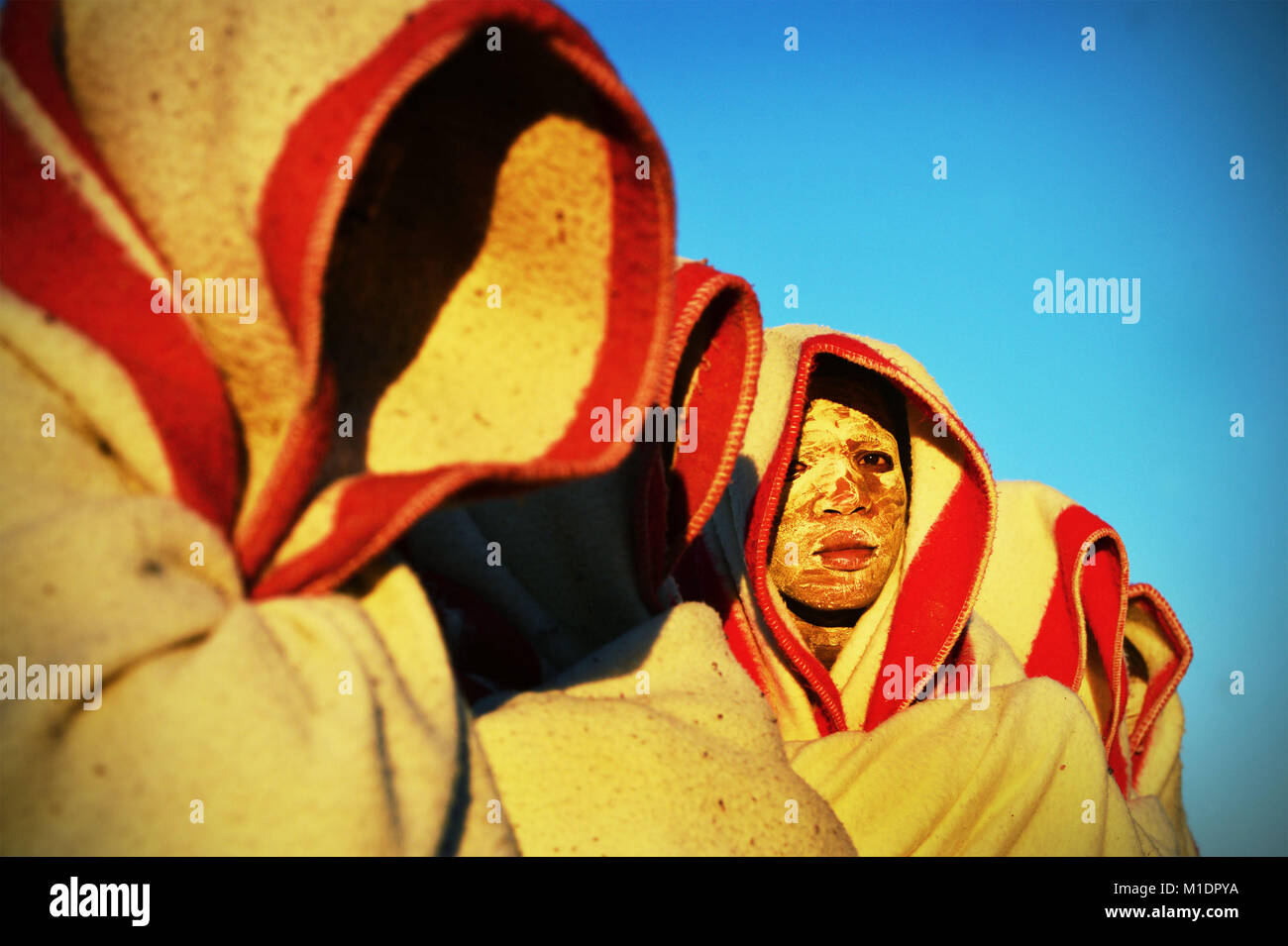 2014-06-20. Initiates are seen smeared with white clay on their face, covered in red and white blanket. during a initiation ritual. Stock Photo