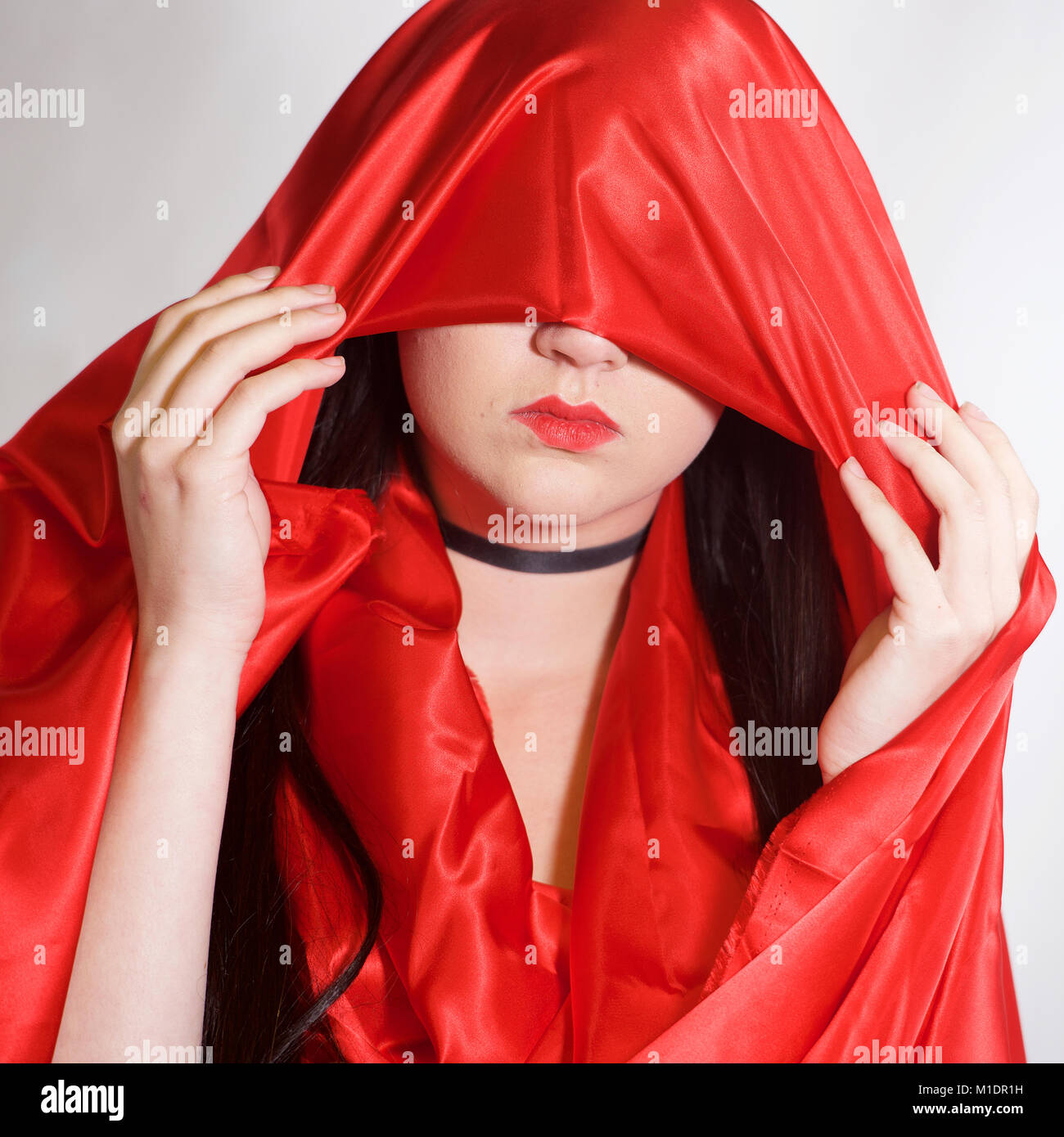 Head and shoulders of a pretty girl with red lipstick and red fabric Stock Photo