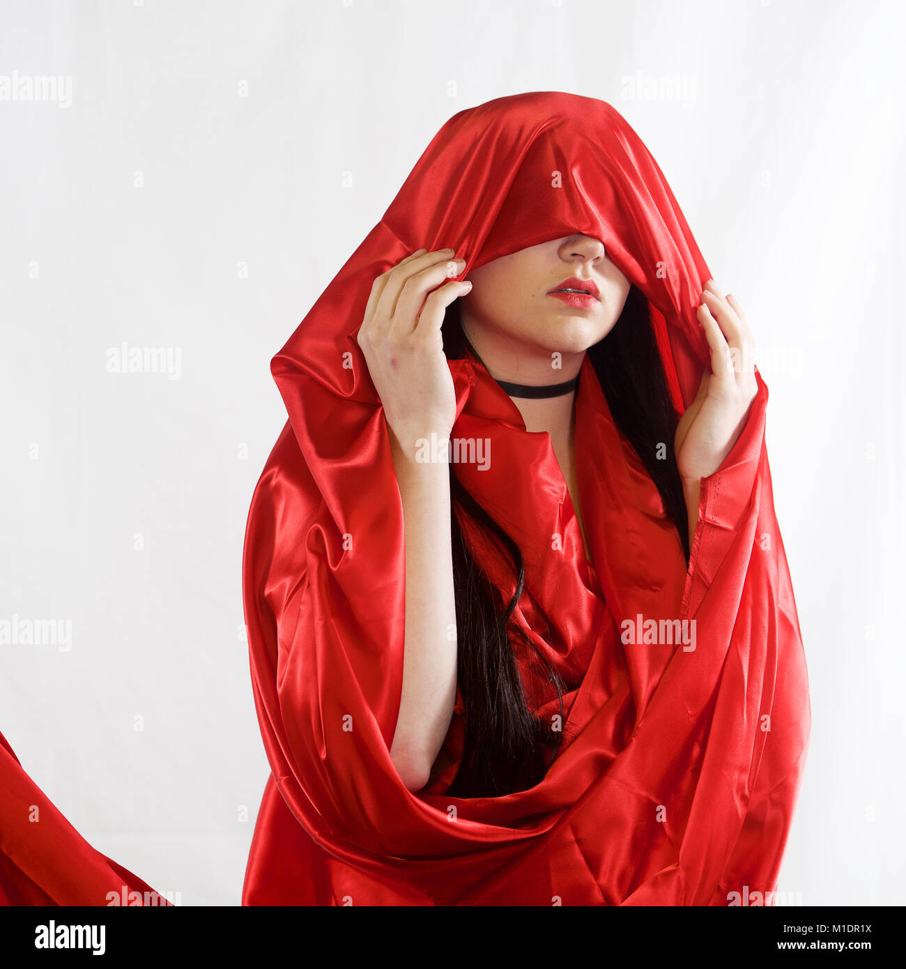 Head and shoulders of a pretty girl with red lipstick and red fabric Stock Photo