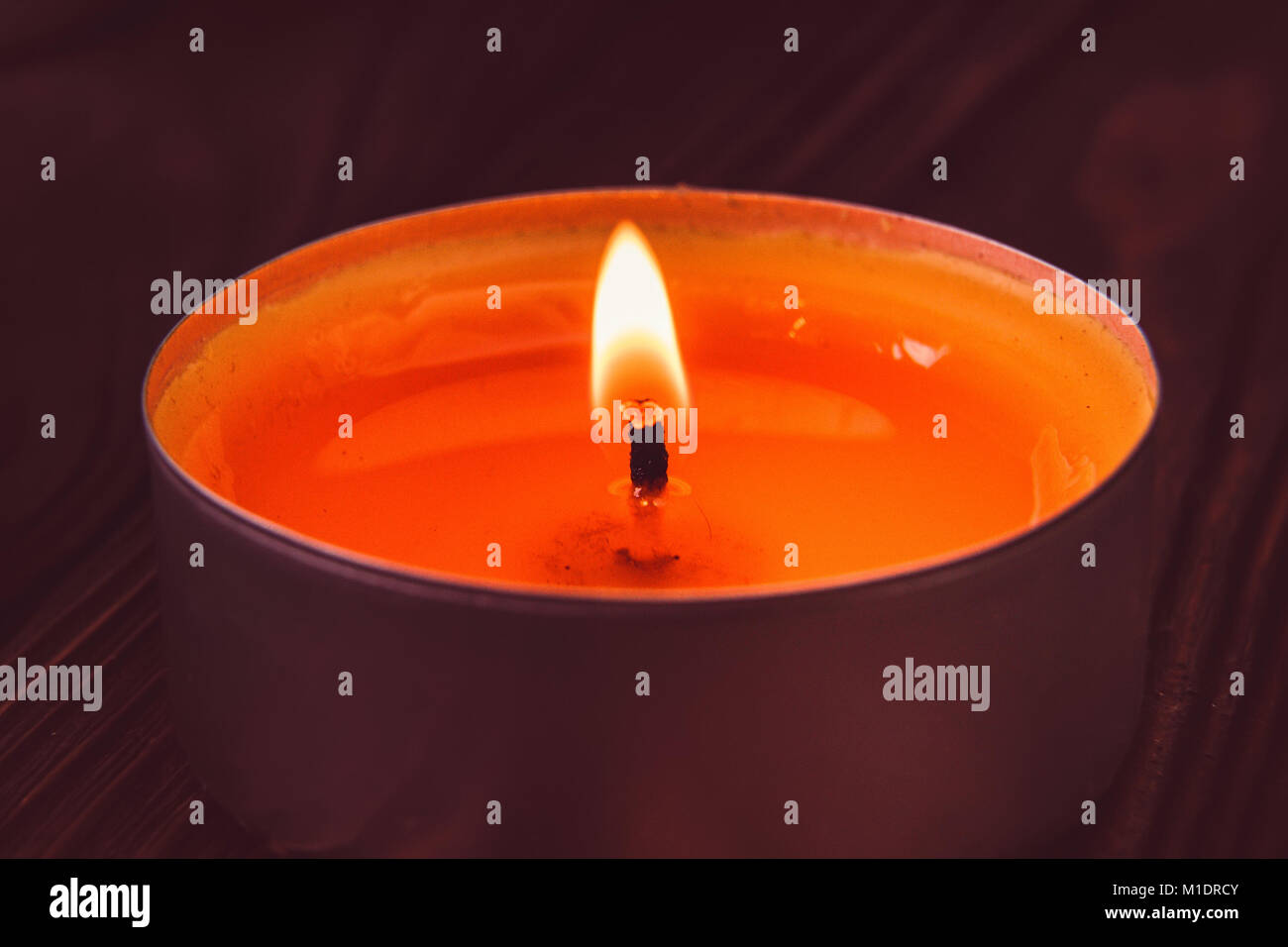 Small white candle burns on dark background Stock Photo
