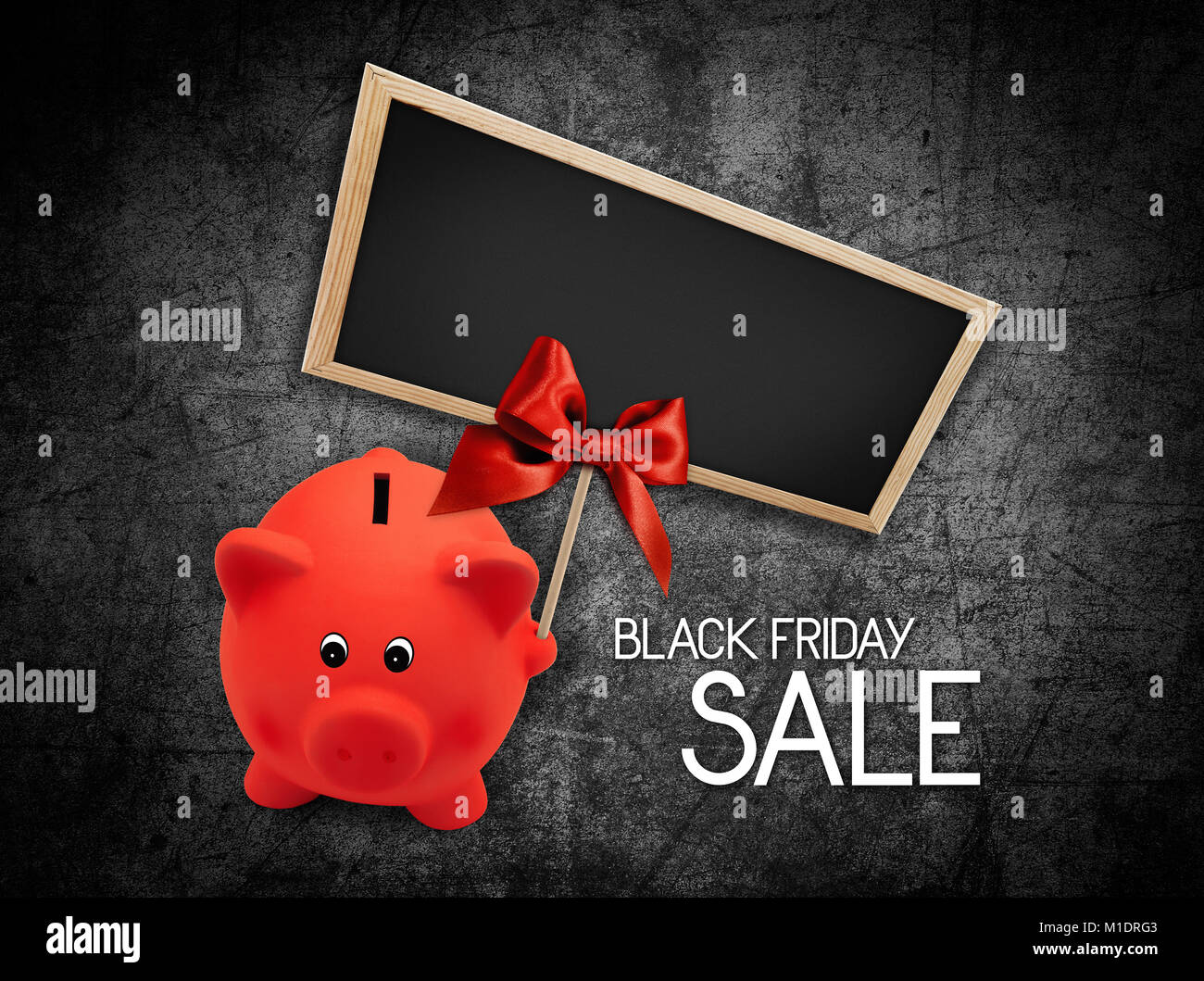 Black Friday sale text blackboard and piggy bank with red ribbon bow on black background Stock Photo