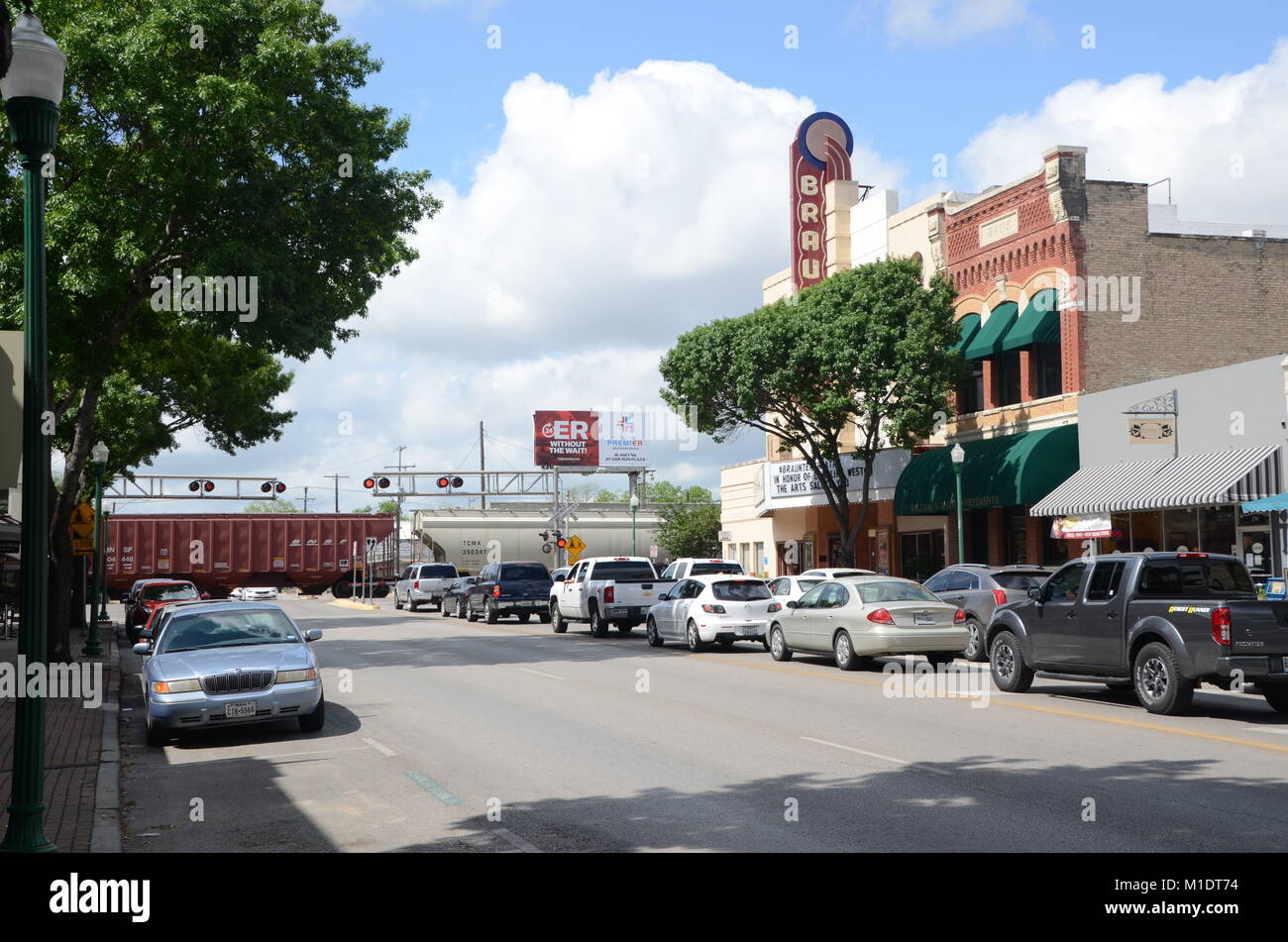 cars wait on w san antonio st new braunfells for a passing freight train texas USA Stock Photo