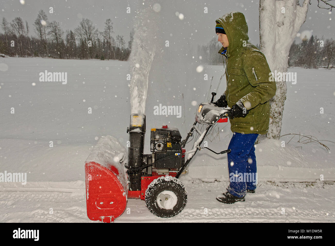 A male teenager with a snow blower in snowy weather Stock Photo