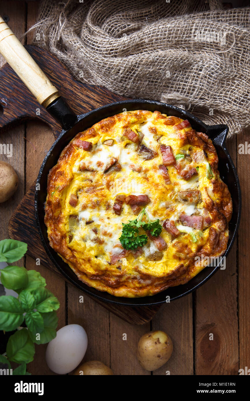 French omelette Savoyarde with bacon, cheese and leeks in fry pan