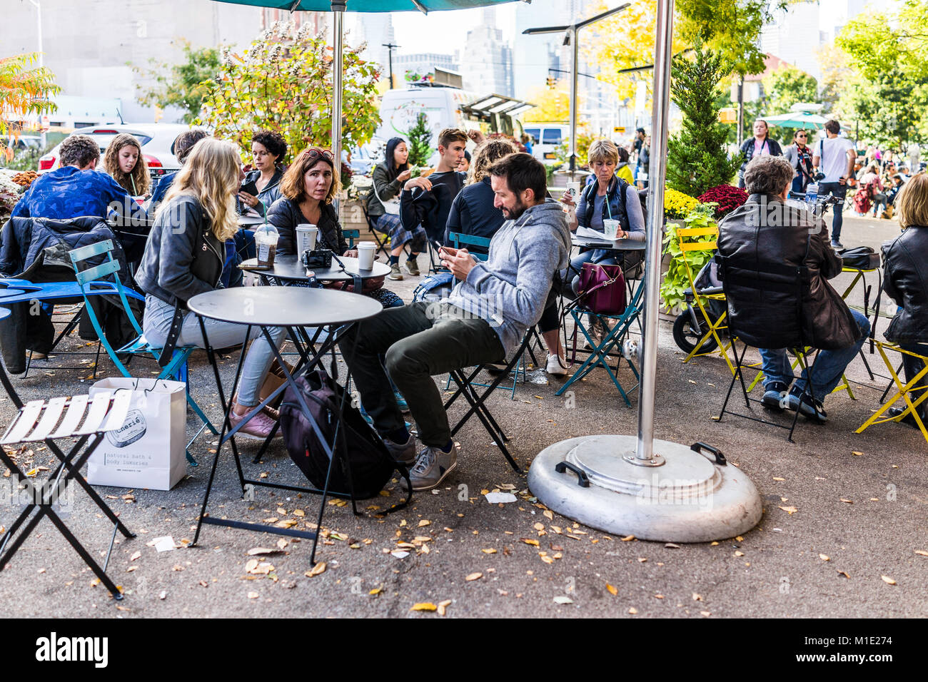 Brooklyn, USA - October 28, 2017: People crowd sitting eating famous restaurant food by cafe outside, Starbucks coffee drinking Stock Photo