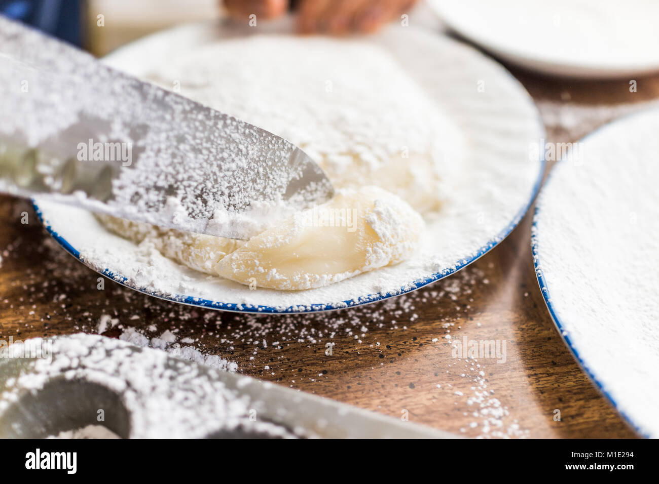 Kitchen knife cutting piece of mochi sticky glutinous rice cake dusted