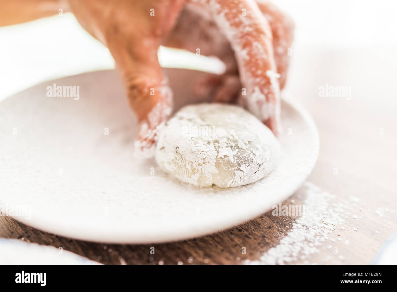 Hands shaping piece of mochi sticky glutinous rice cake dusted with