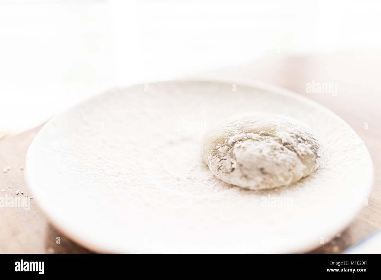 Hands shaping piece of mochi sticky glutinous rice cake dusted with